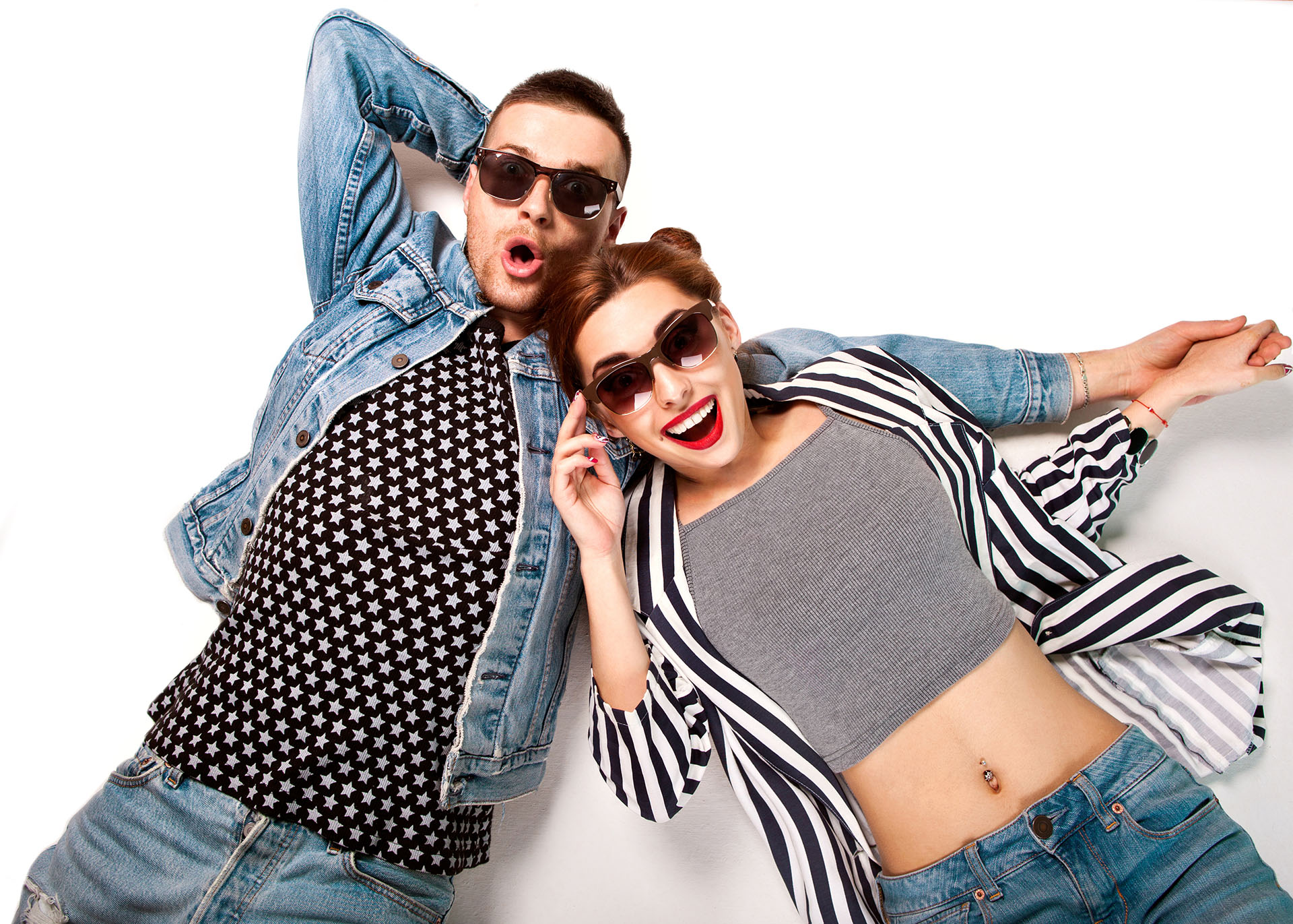 fashion couple in sunglasses lies on a white background, smiling happily and surprised