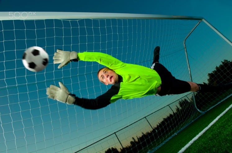 Caucasian soccer goalie jumping