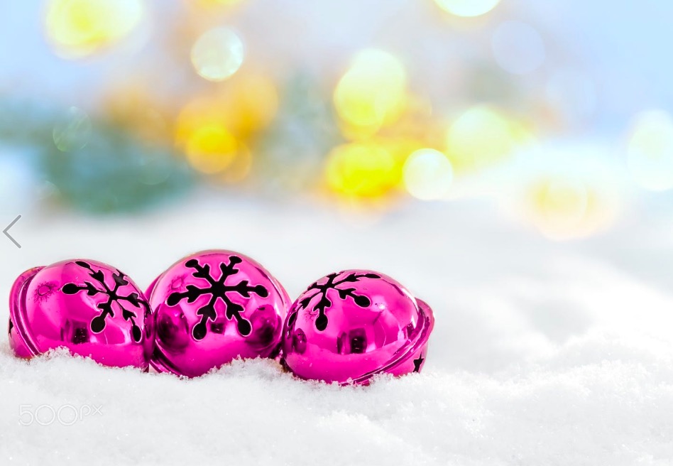 Christmas jingle bells on snowy background and defocused lights