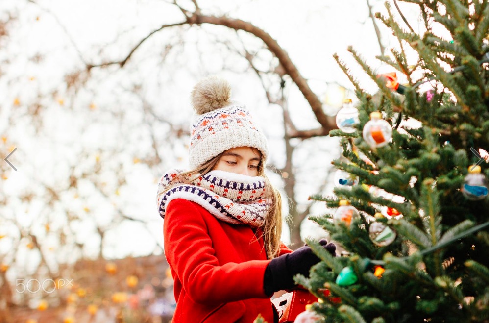 Girl putting Christmas decoration on tree