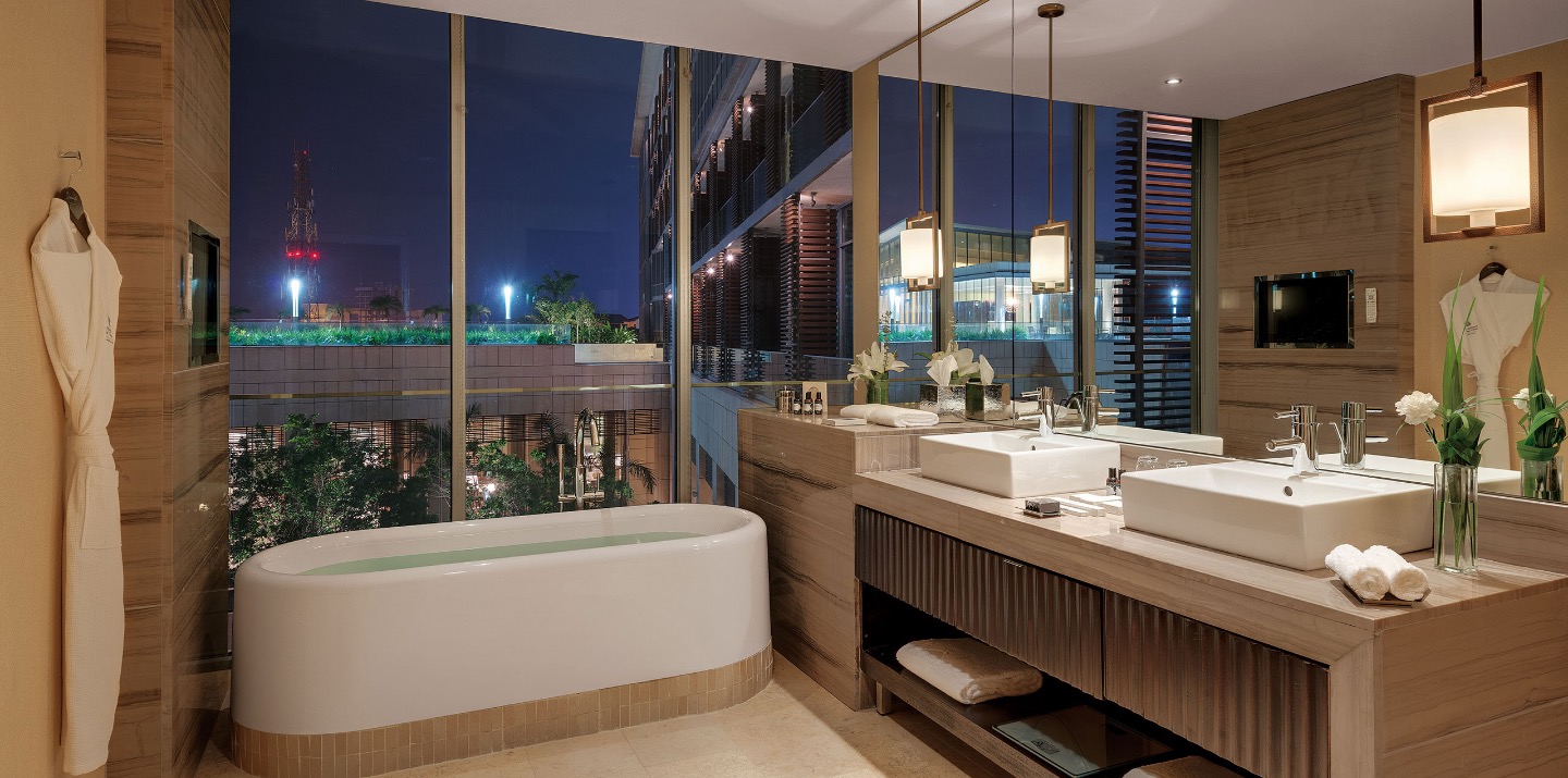 a-bathroom-with-large-mirrors-and-windows-overlooking-the-courtyard-of-the-kempinski-hotel-in-accra-ghana