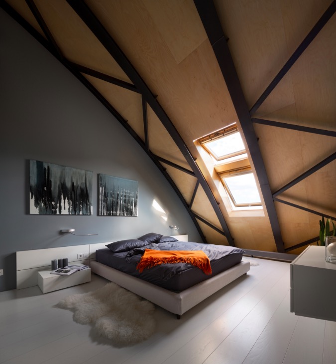 Bedroom in a modern loft apartment, formerly a commercial building, with an arcing steel beam roof line in Kiev, Ukraine