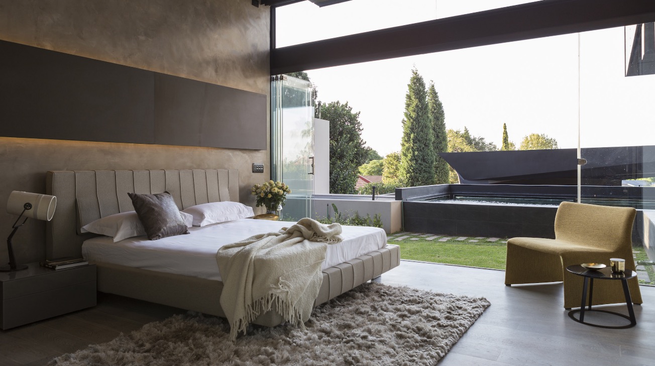 Modern bedroom opens onto private pool area through folding glass doors in this home in Johannesburg, South Africa