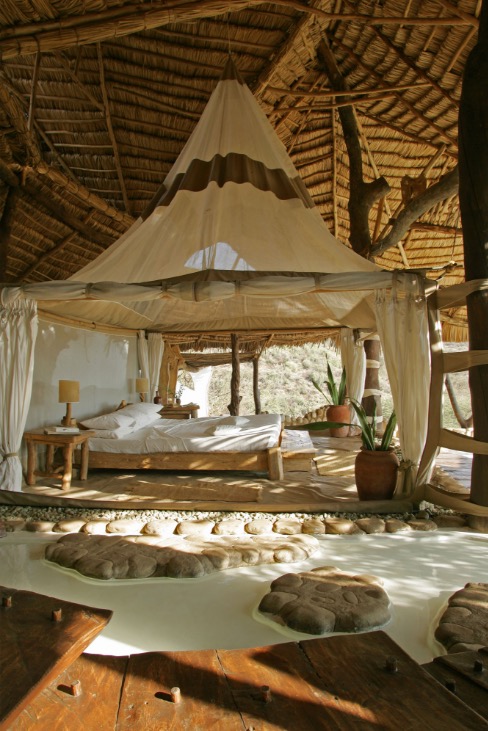 Tented bedroom beneath large thatched roof overlooks the bush in Southern Kenya