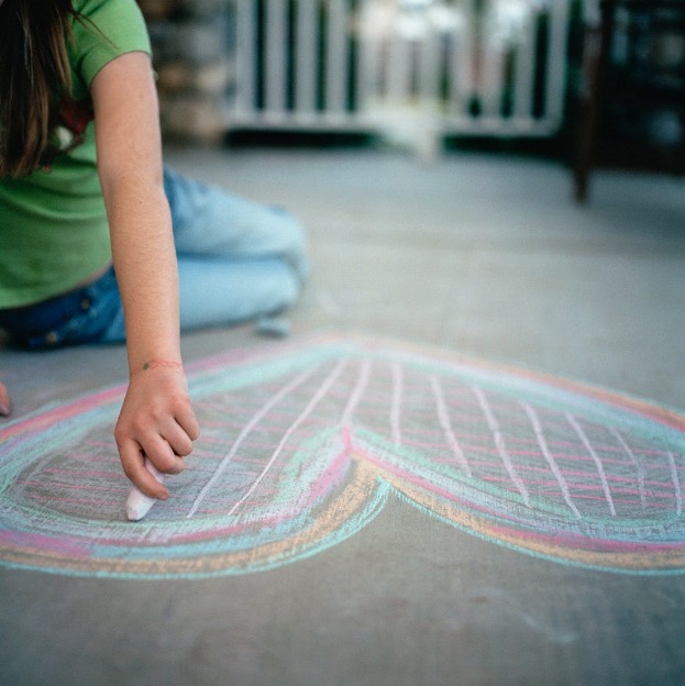 Young girl drawing a heart in chalk
