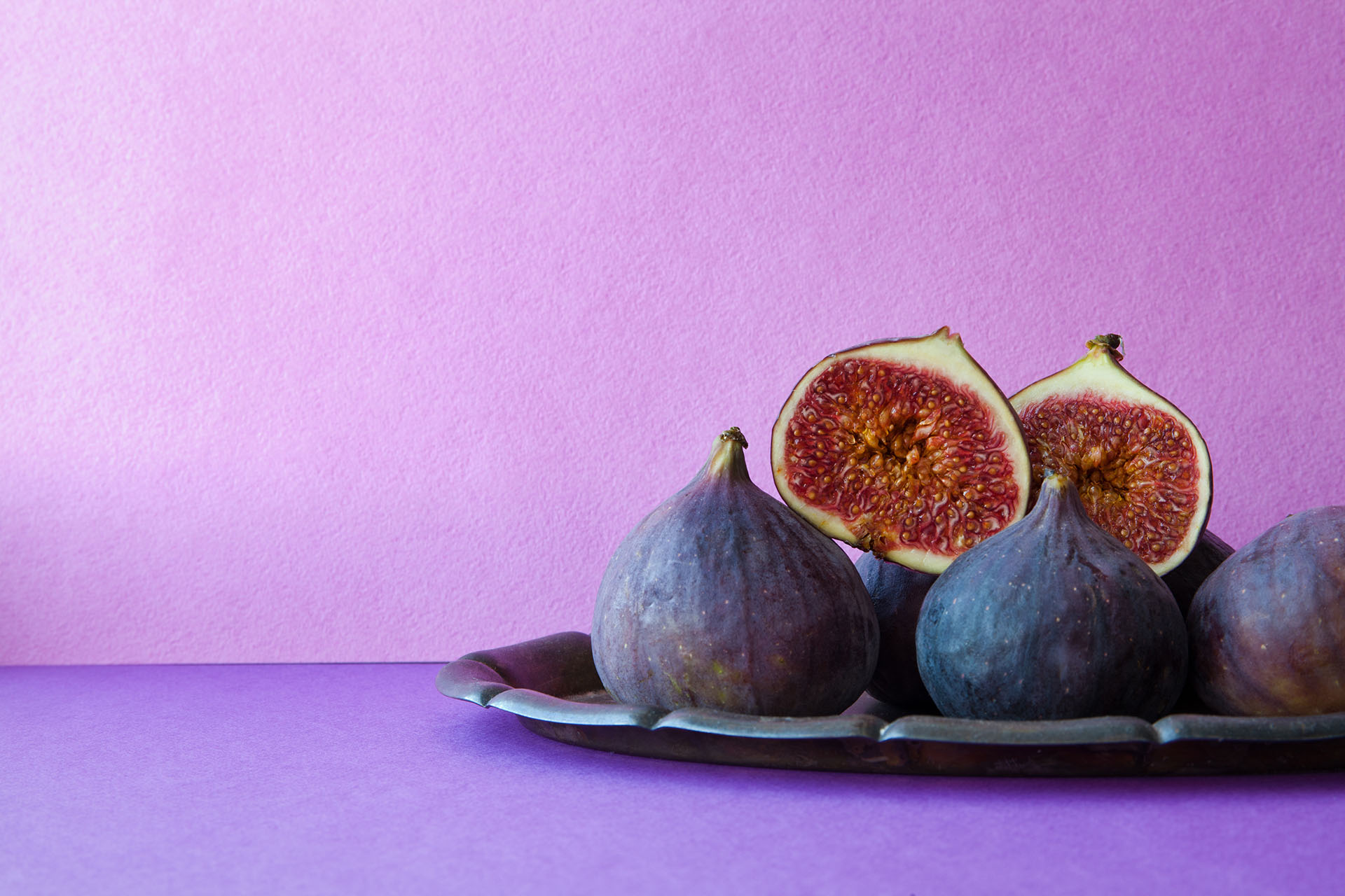 Bright still life organic fig fruits on an old tray, beautiful purple violet background