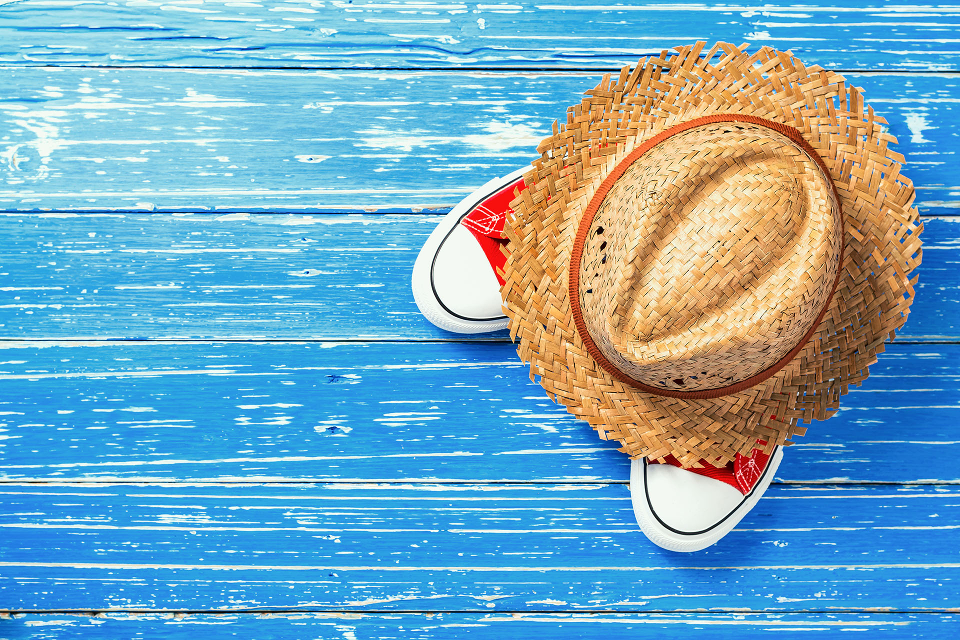 Straw hat and red shoes on distressed blue wood board