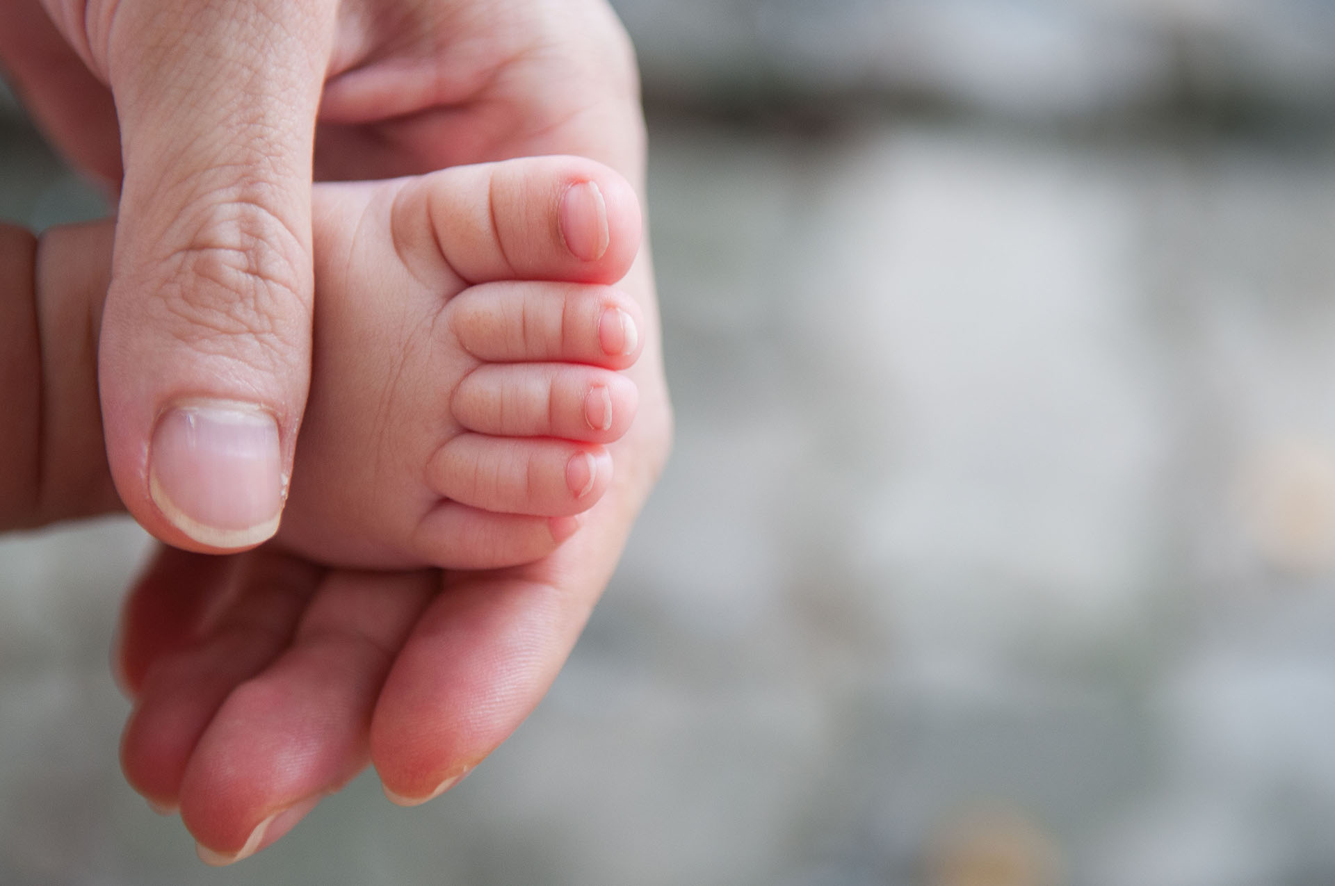 Close up of cute asian girl newborn foot with hands of her mom _ dad