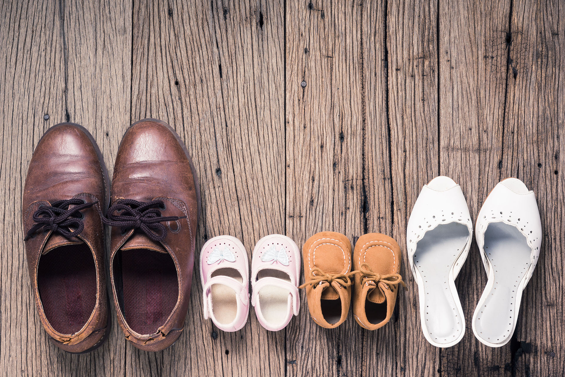 father mother son and daughter shoes on old wood floor, family concept