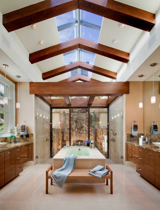 His and hers bathroom with dual showers that look onto a stone fireplace