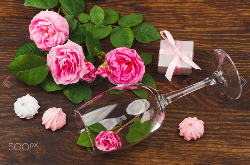 Light pink roses and wineglass on the wooden table