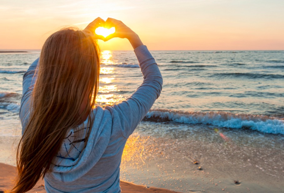 girl-holding-hands-in-heart-shape-at-beach