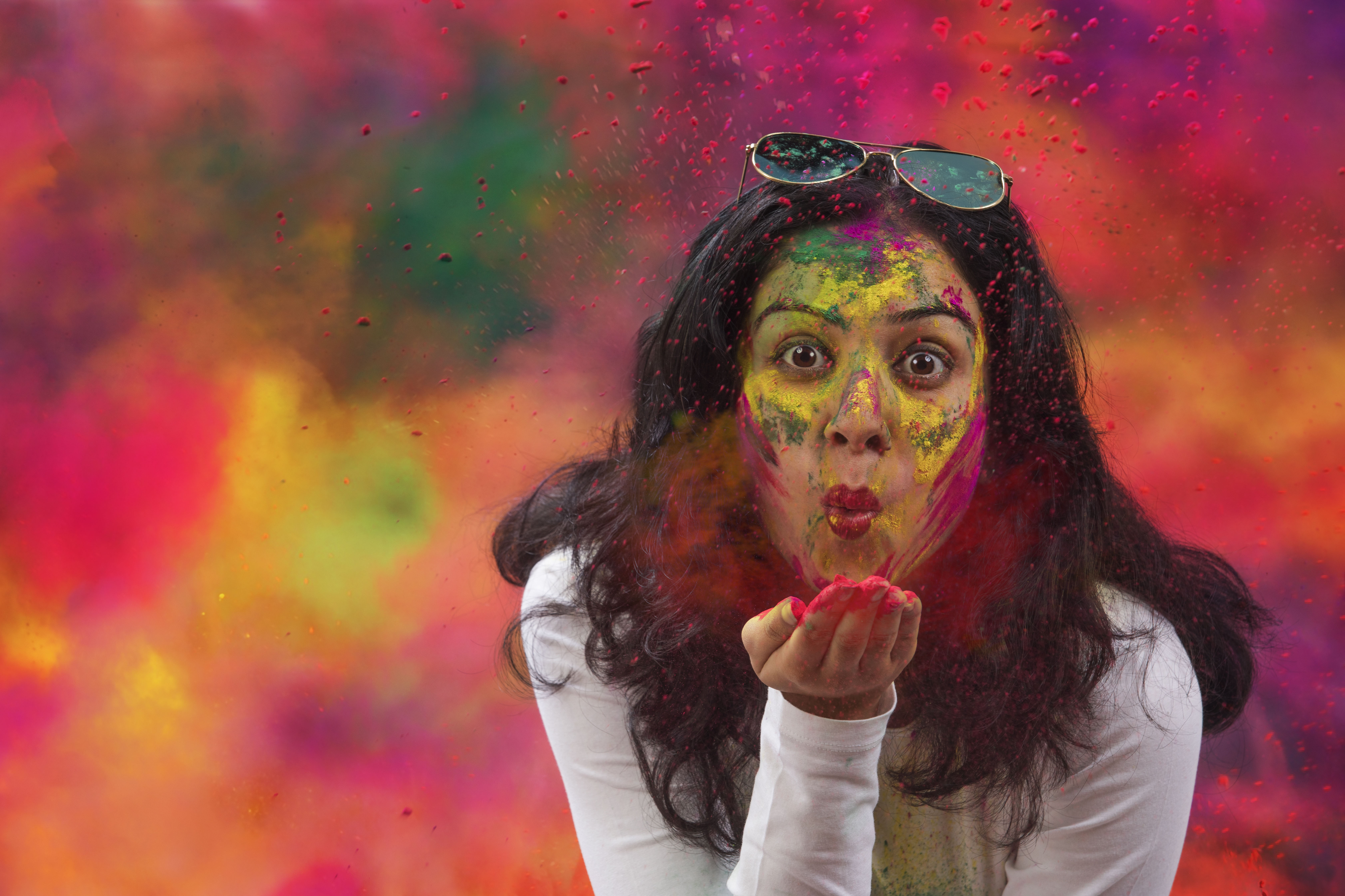 Portrait of an Indian Woman celebrating Holi by blowing Holi powder