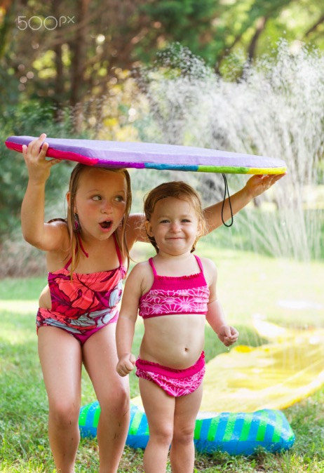 Caucasian girls playing in sprinkle