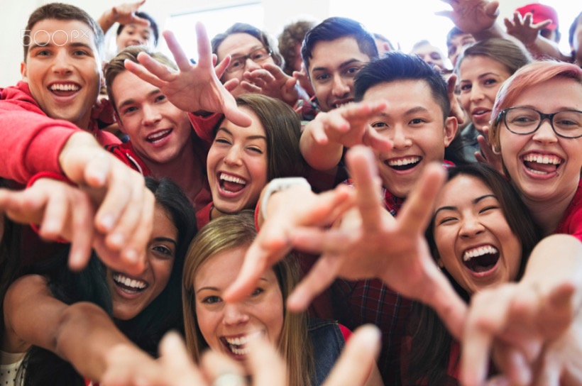 Portrait of large group of students cheering at college