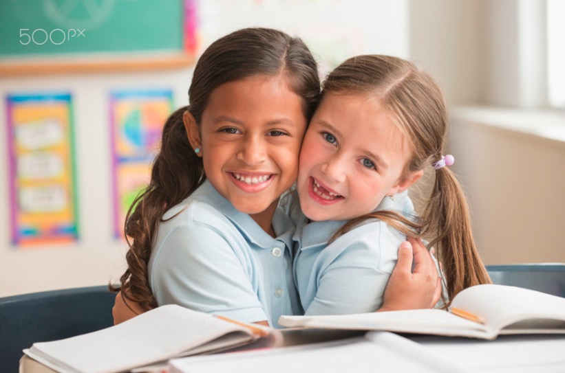 Smiling students hugging in classroom
