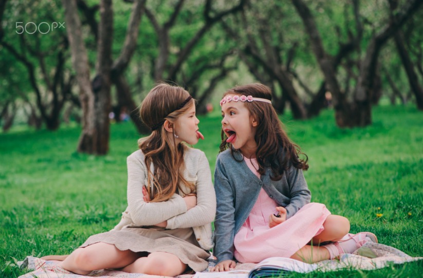 two kid girlfriends showing tongue to each other