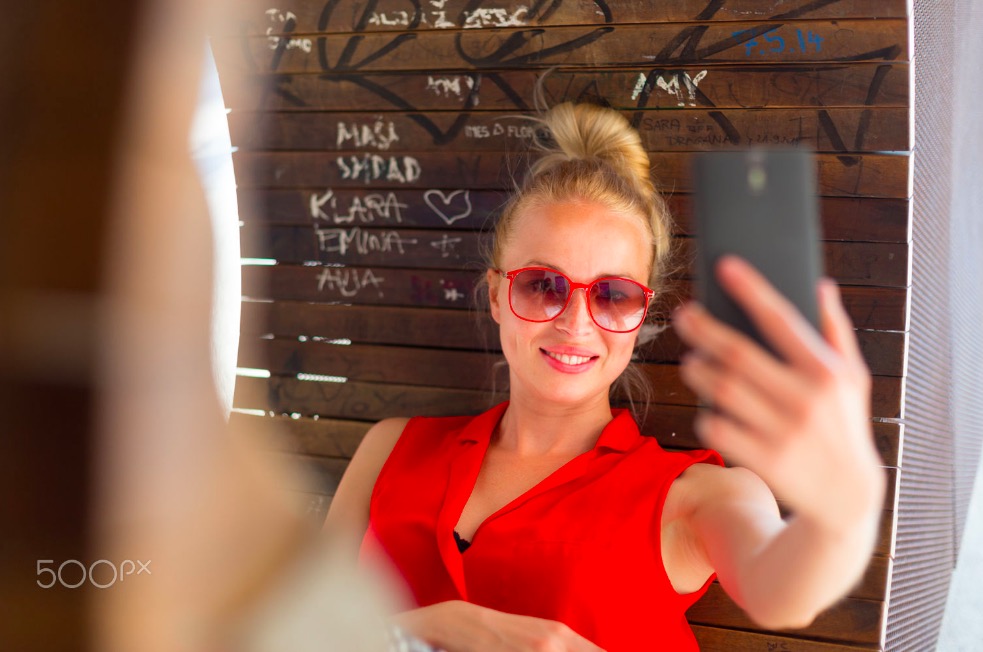 Young cheerful lady taking selfie