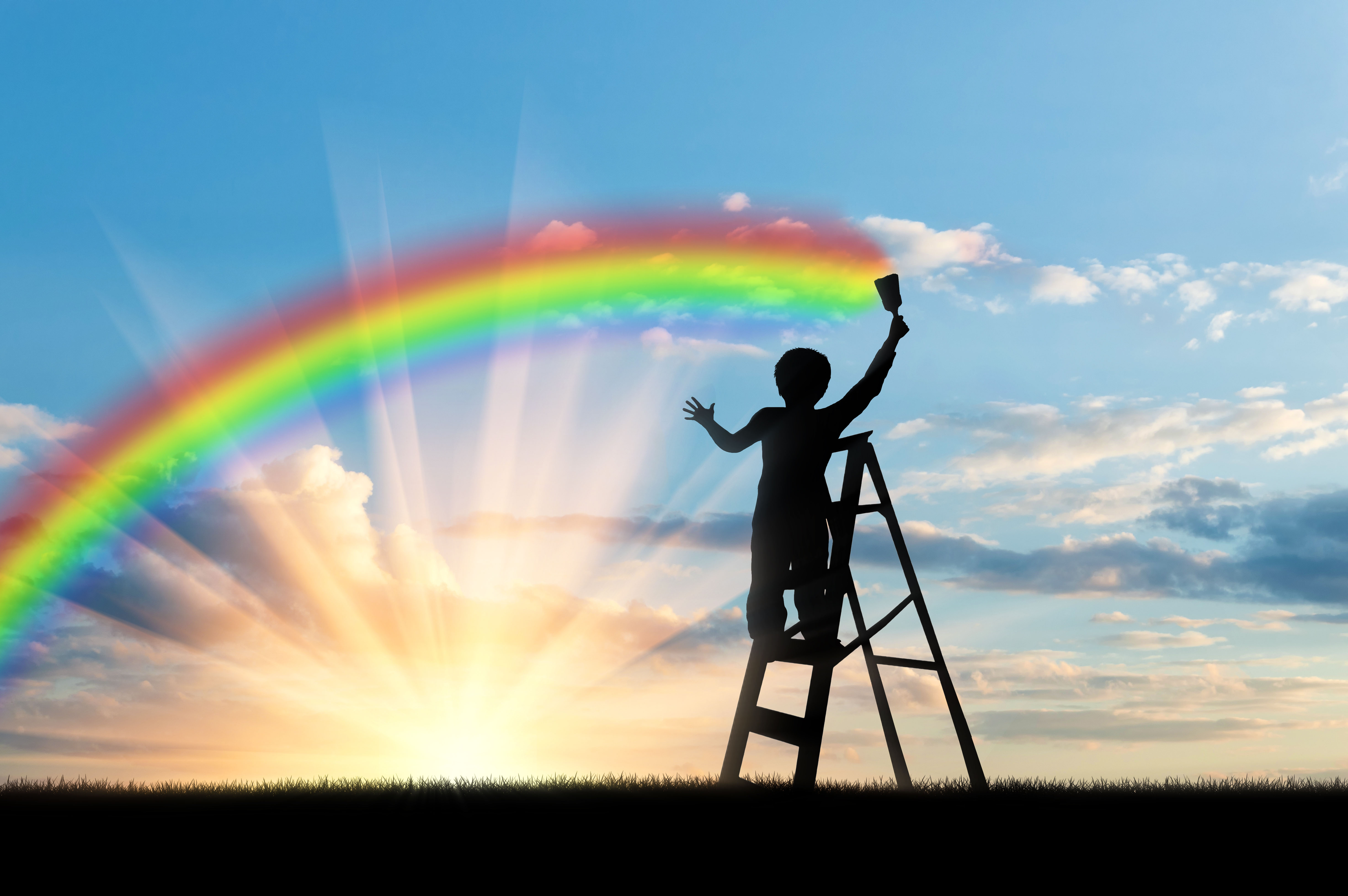 Child paints a rainbow in the sky at sunset