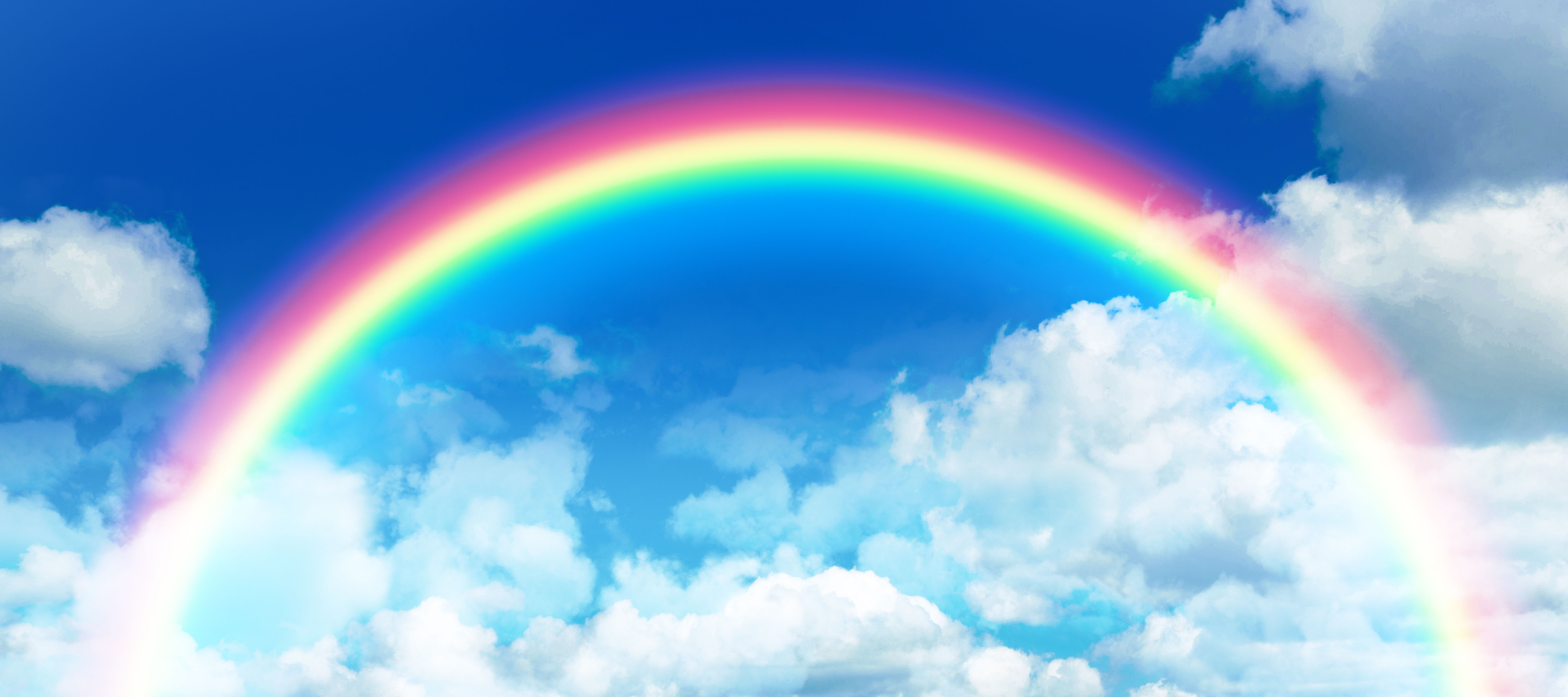 Composite image of rainbow against idyllic view of clouds against sky