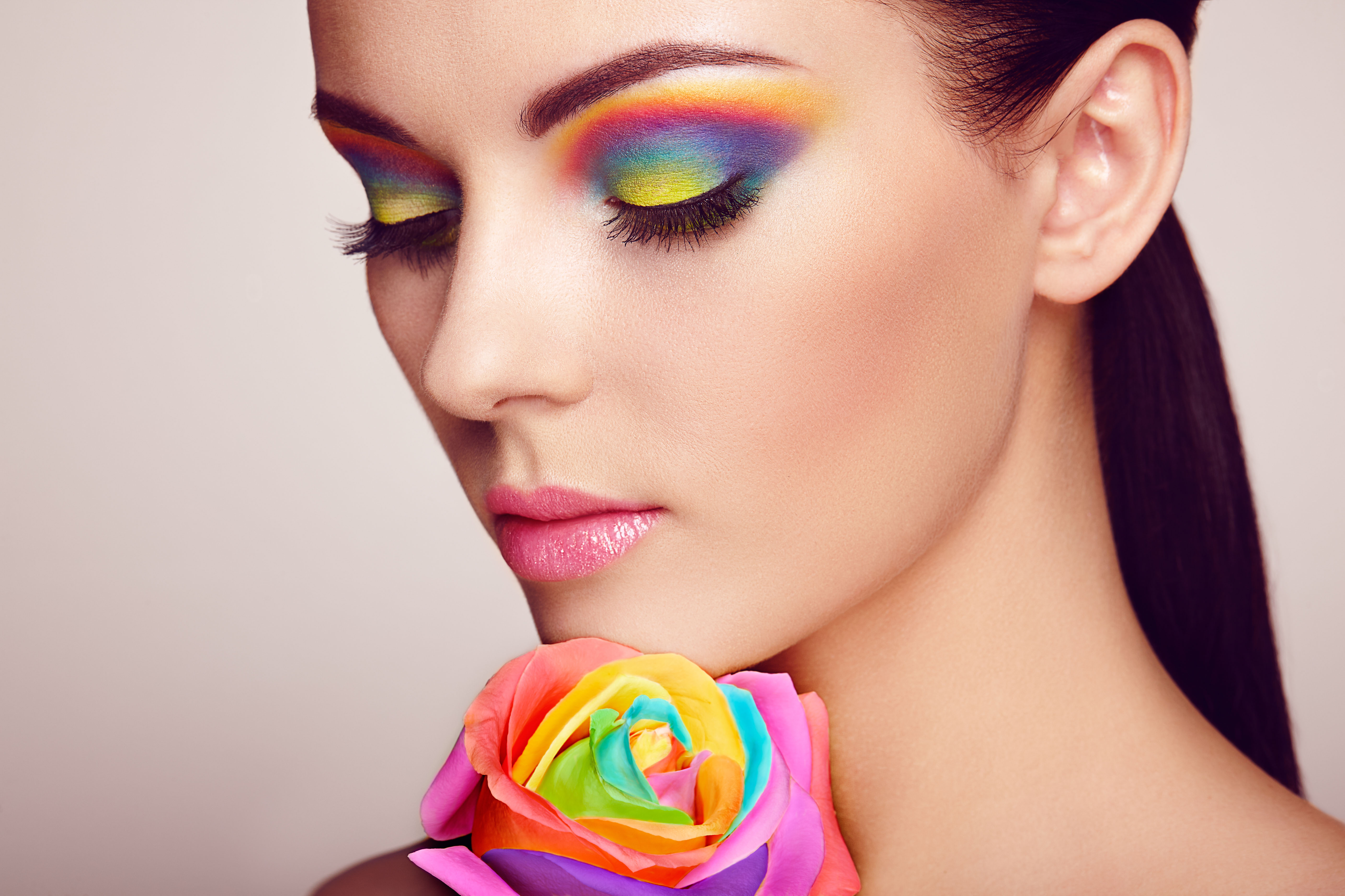 Portrait of beautiful young woman with rainbow rose