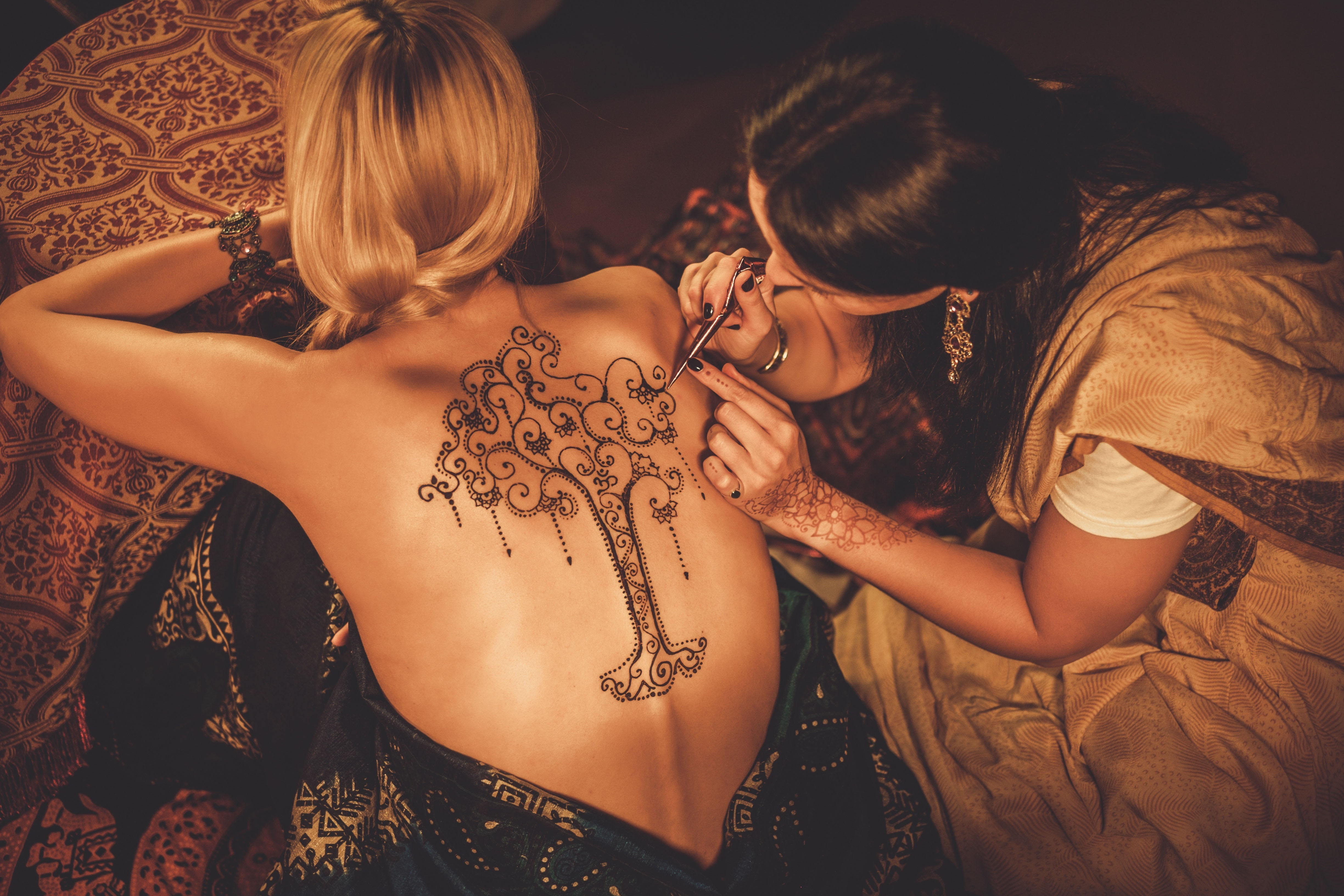 Drawing process of henna menhdi ornament on woman's back