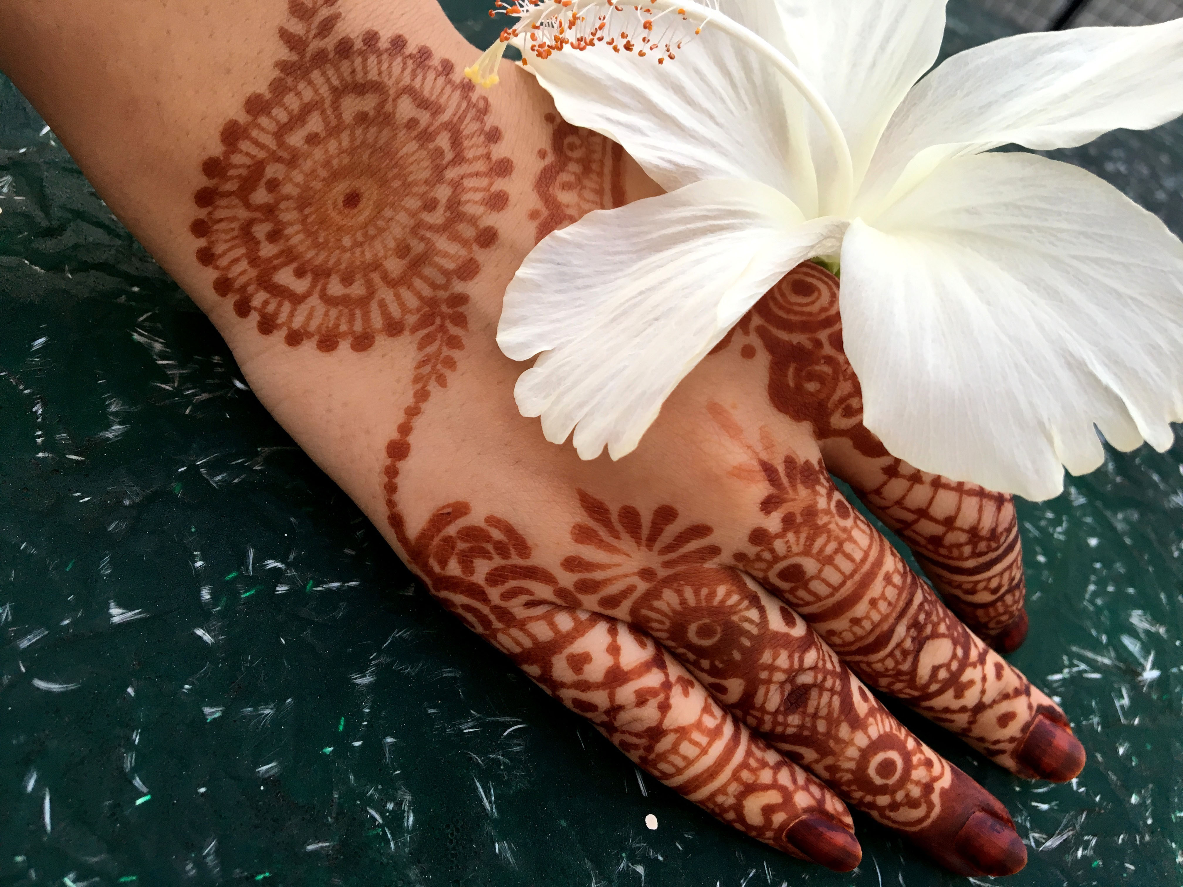 Mehndi hands with white hibiscus flower