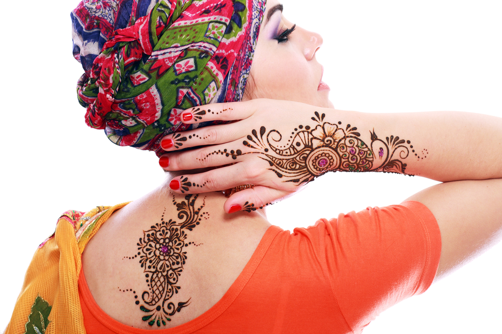 Beautiful woman arabian make up and turban on head with detail of henna being applied to hand and back