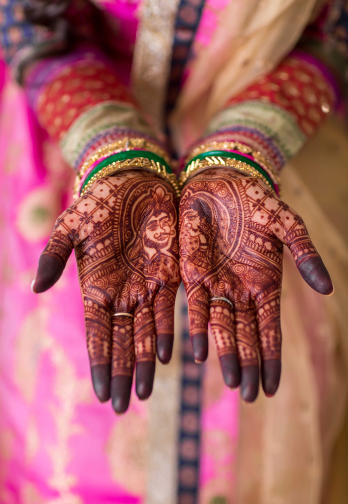 Bridal wearing wedding bangles and showing mehndi design