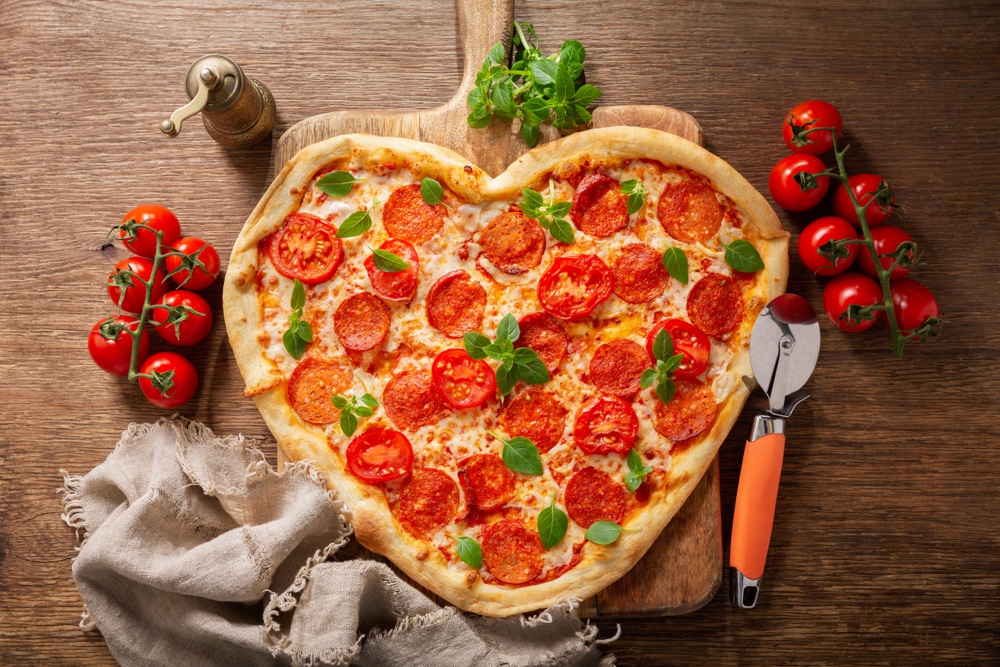 Heart shaped pepperoni pizza with green basil