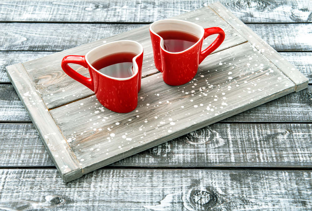 Heart shaped cups with red drink on rustic wooden background
