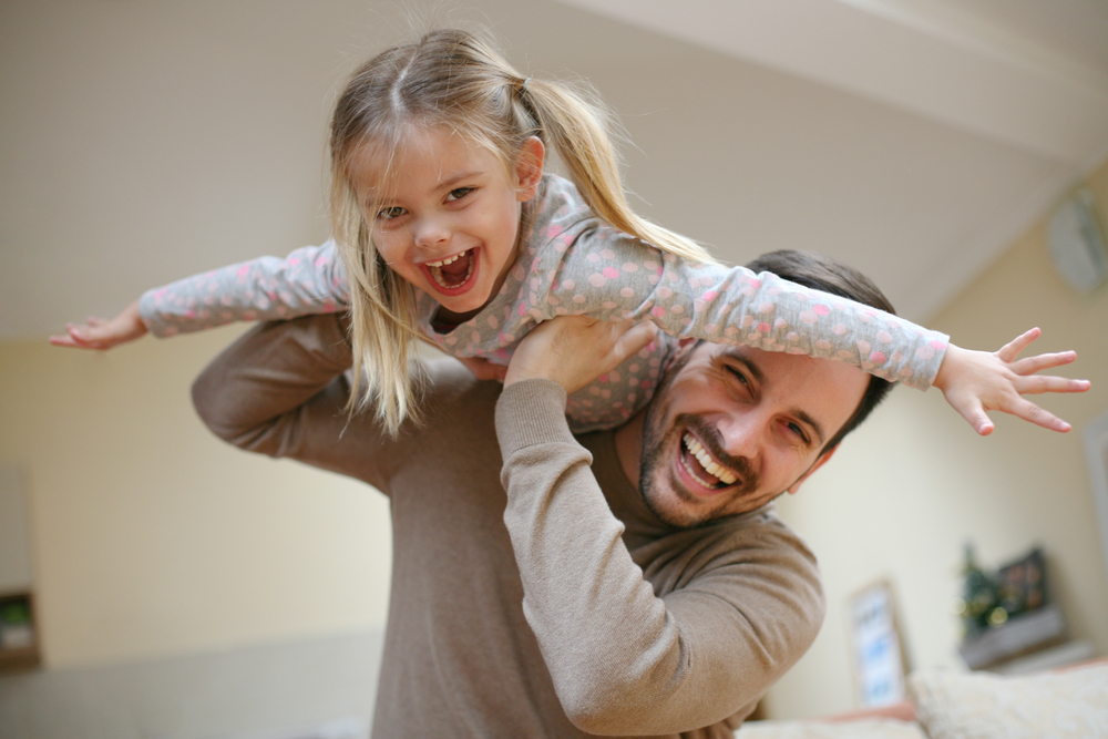 Cute young daughter on a piggy back ride with her dad