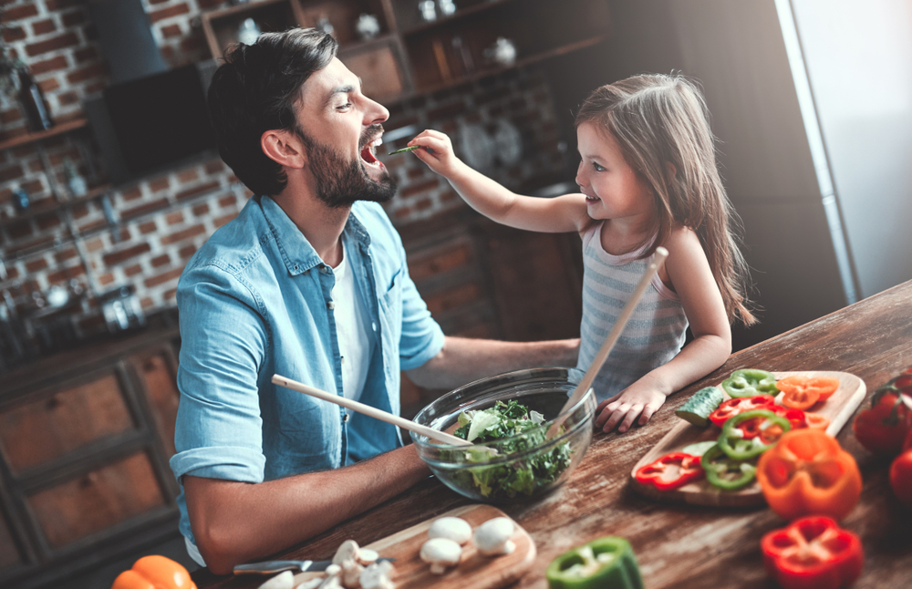 Handsome man and his little cute daughter are cooking on kitchen