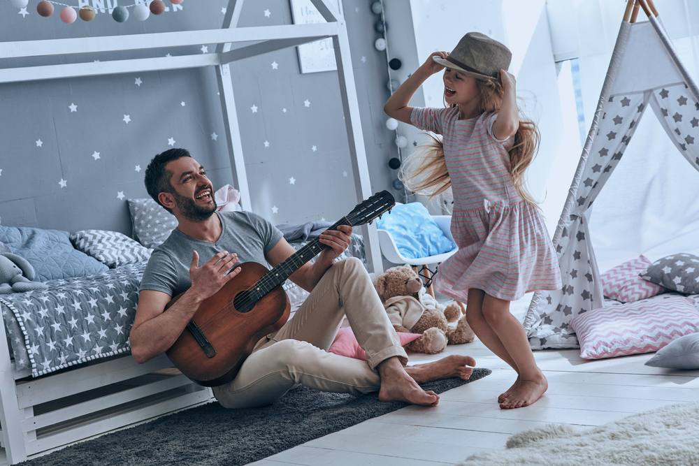 Young father playing guitar for his little daughter