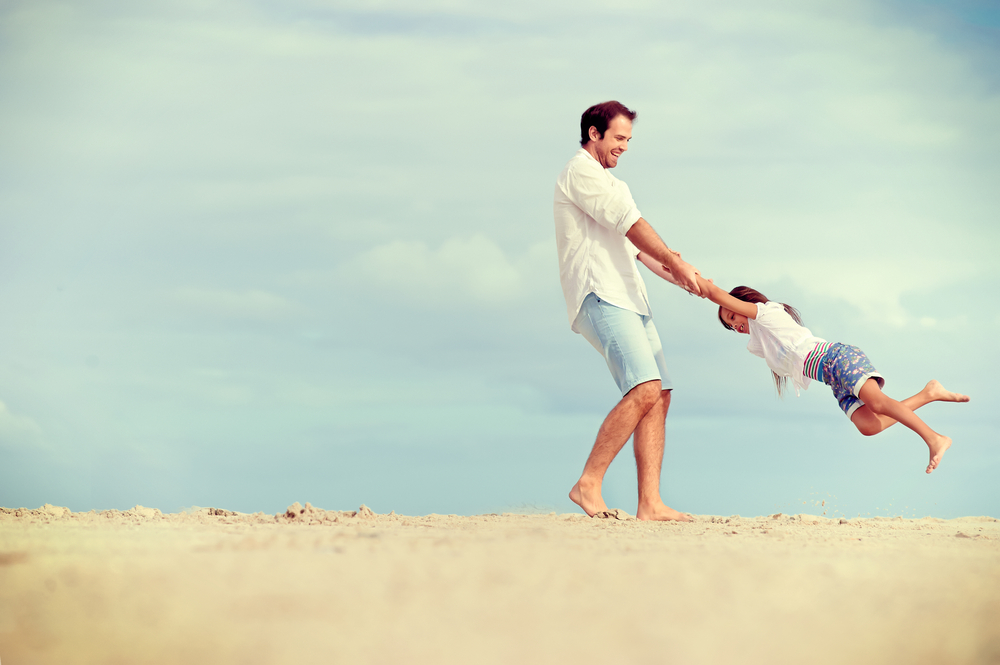 father and daughter playing together at the beach carefree