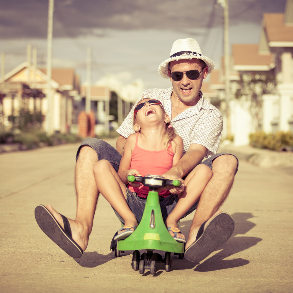 father and little daughter playing near a house at the day time